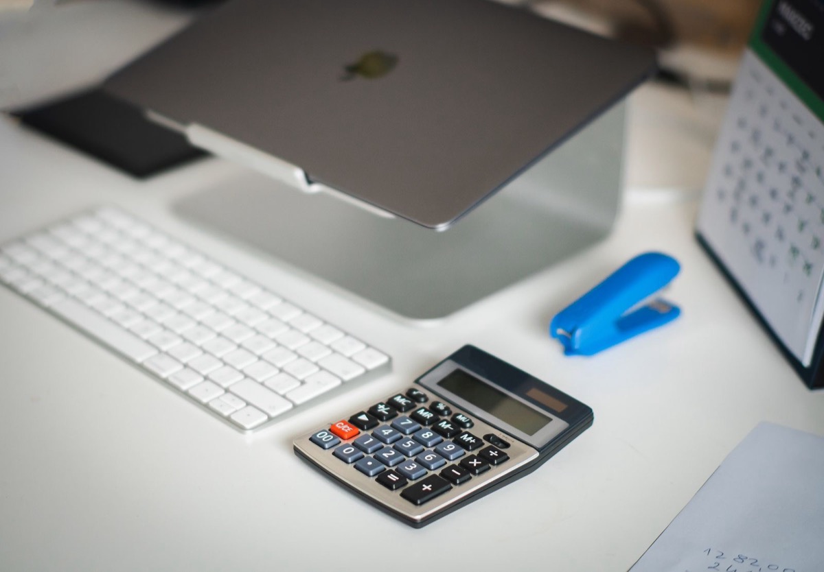 A laptop, a calculator and a desk calendar on a tidy office desk