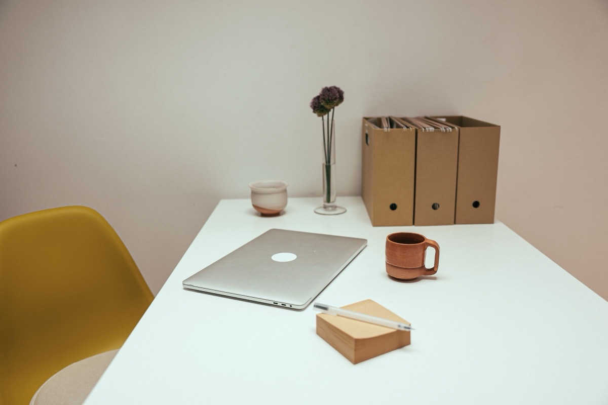 A laptop, a cup and box files on a tidy office desk
