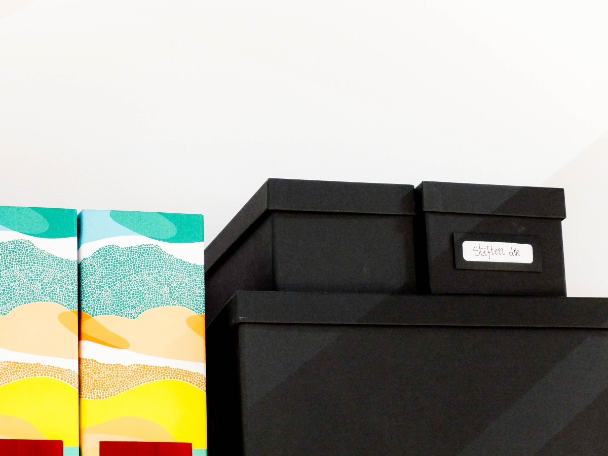 Black storage boxes stacked on a shelf