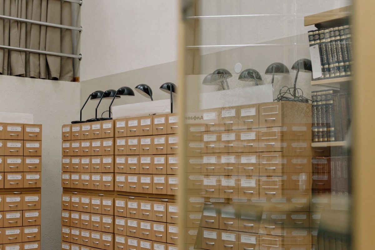 Rows of wooden archive drawers under desk lamps