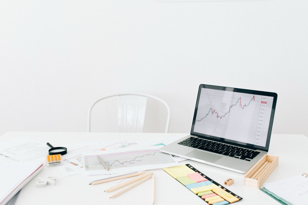 A laptop with a spreadsheet, a calculator and a folder of documents on an office desk