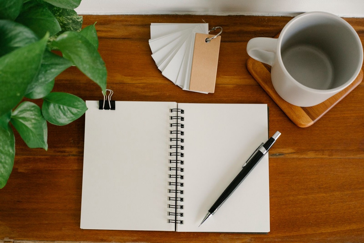 An empty notebook and a pen on a wooden desk