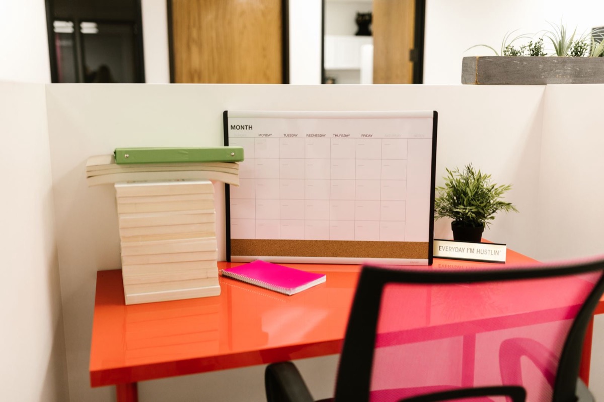 An office desk with a wall planner