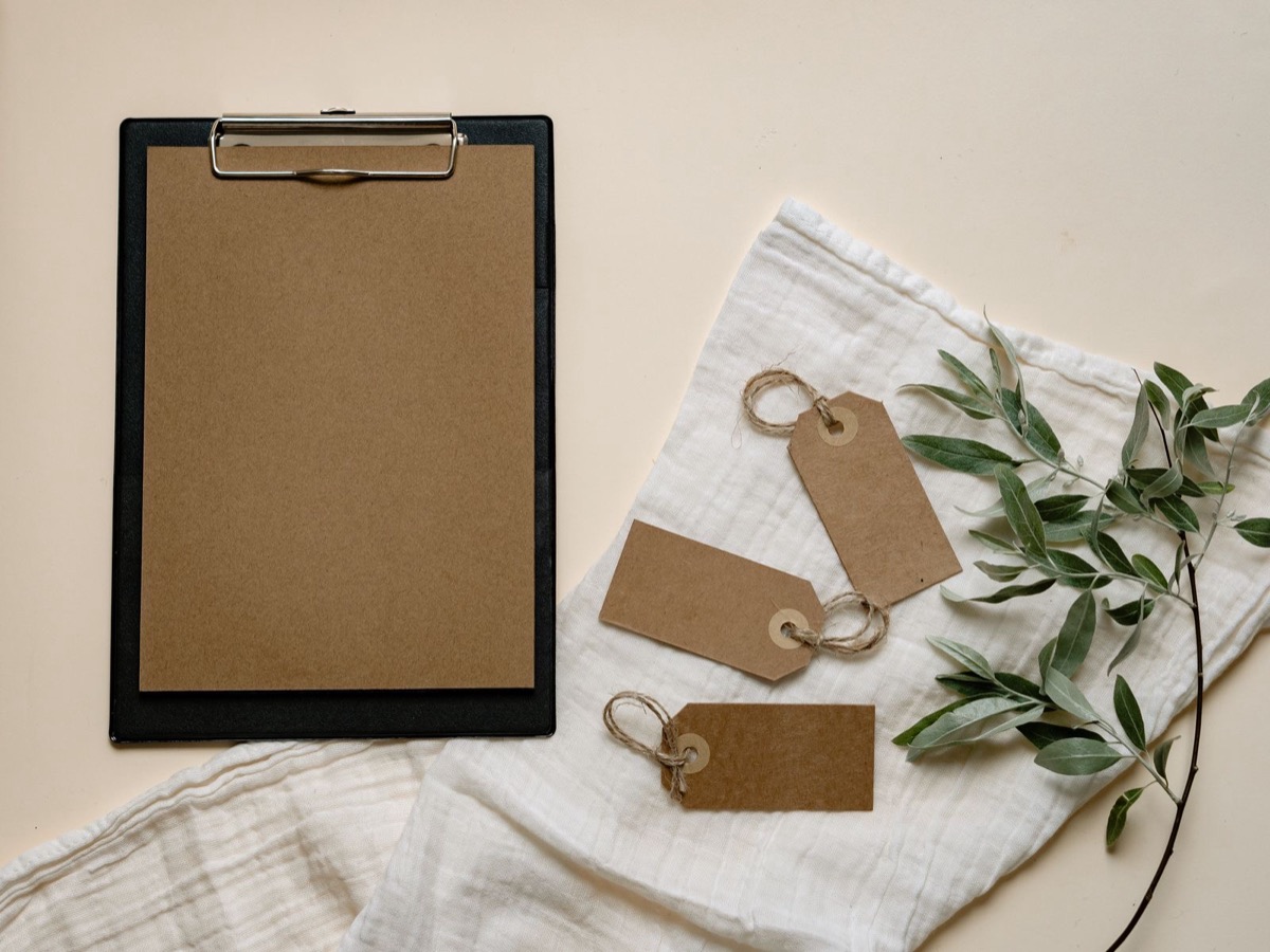 A brown clipboard and tags on linen