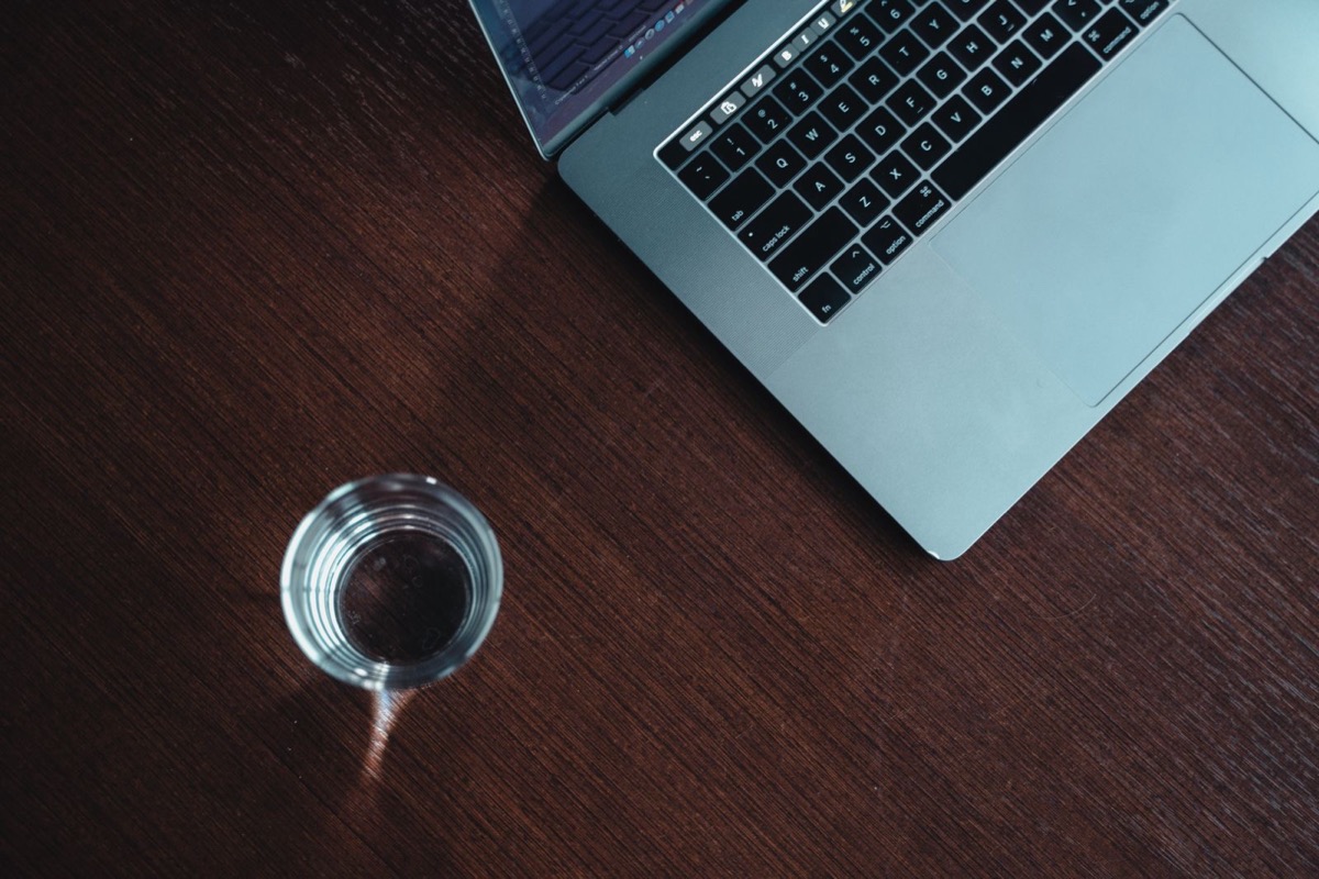 A laptop and a glass on a dark wooden desk
